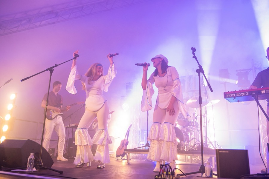 The band across the full width of the stage with the drum kit lit at the back