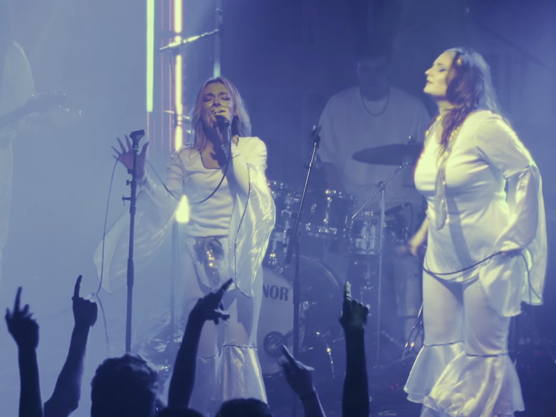 The two lead vocalists in white ABBA-era costume mid-song at Chalk in Brighton, with hands raised in the crowd below