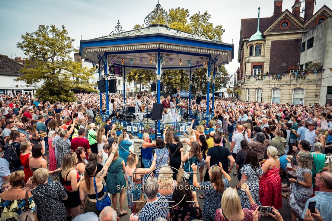 A large daytime crowd packed around a Victorian bandstand in Horsham town centre as the band plays